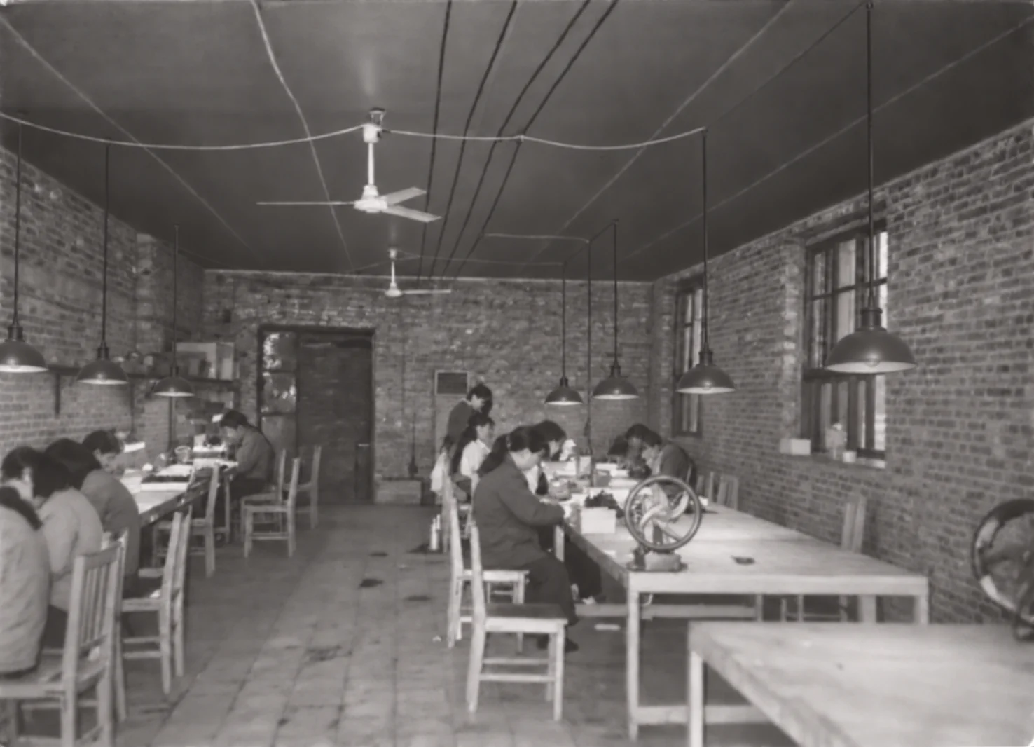 Baosheng workshop, 1960s — workers at the benches under strip lights